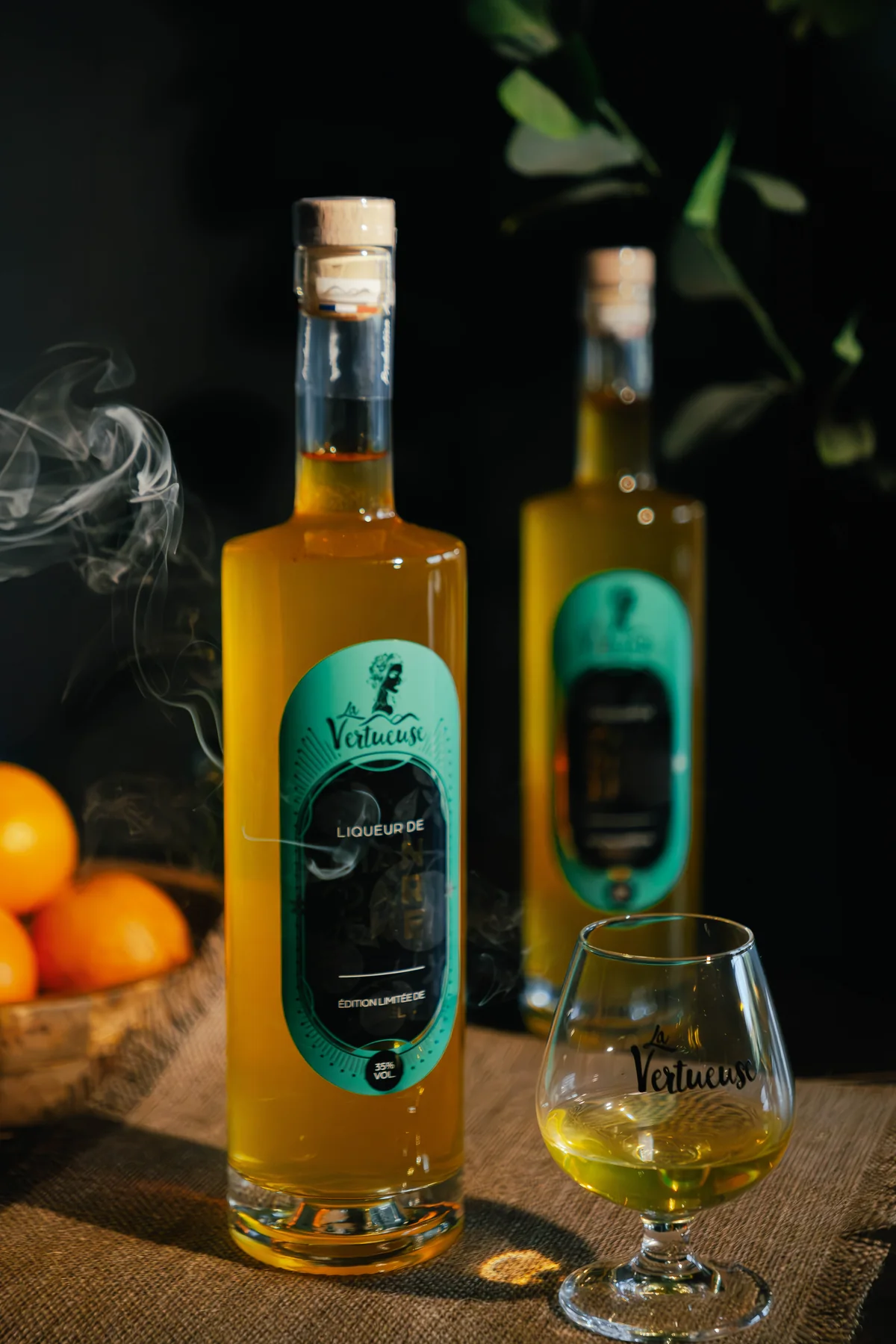 Liqueurs La Vertueuse présentées dans une mise en scène sombre et végétale