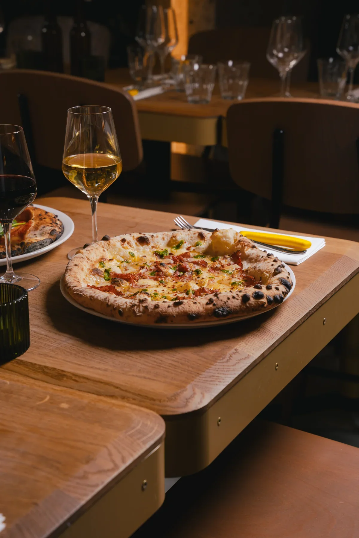 Pizza de bistrot servie à table avec du vin, dans une lumière chaude
